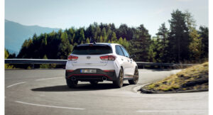 Hyundai i30 n drive n limitována edice hb 12 bílá barva pohled zezadu při jízdě na silnici s pozadím krajiny
