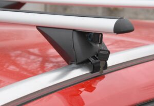 střešní nosiče Compass integrované podelníky na červené střeše auta a zasunutým klíčem