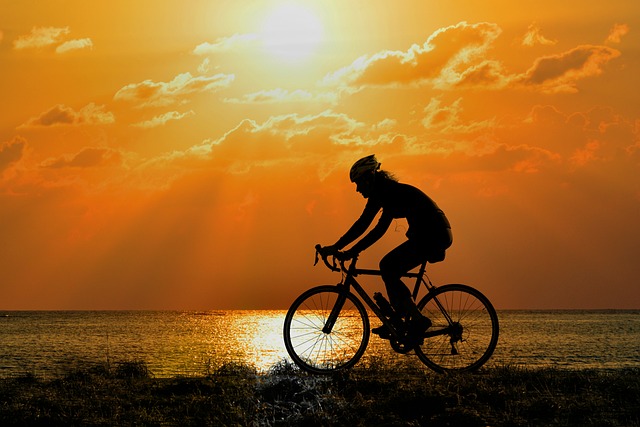 Silueta cyklisty při západu slunce a oranžové obloze